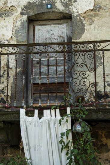 Located in an antique stone structure, this rustic balcony features an ornate railing, flowing