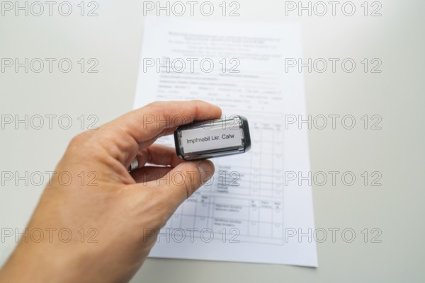 Close-up of a stamp in a hand over a form, Care Connect, vaccination kiosk for refugees, Calw,