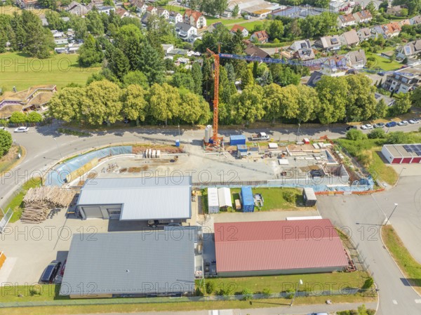 Crane over a construction site in a village landscape with many houses, car park construction,