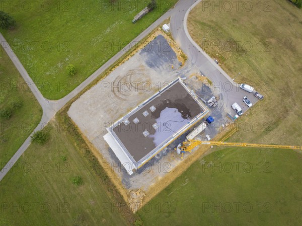 Aerial view of a construction site area with vehicles and a crane next to a partially completed