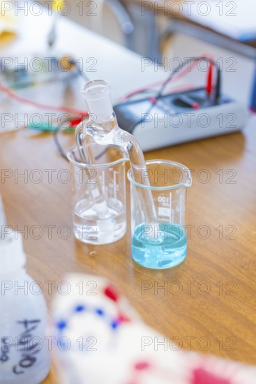 Chemical laboratory with beakers containing a clear and a blue liquid, Battery Research, Nagold,