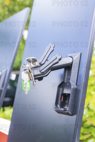A bunch of keys hanging from a lock on a black background in a close-up, installation of a charging