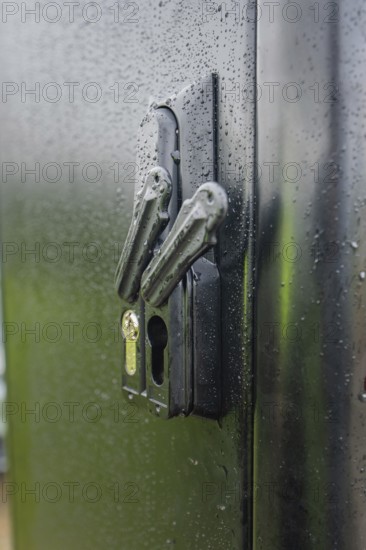 Wet lock on a black door with visible water droplets and reflected light, installation of a