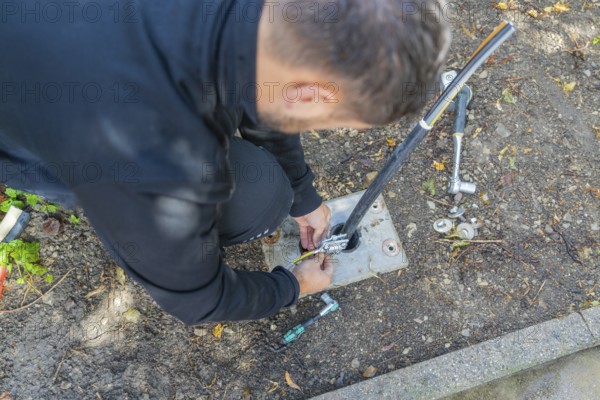 Man installs cables outdoors with tool support, assembly of a charging station for electric cars,