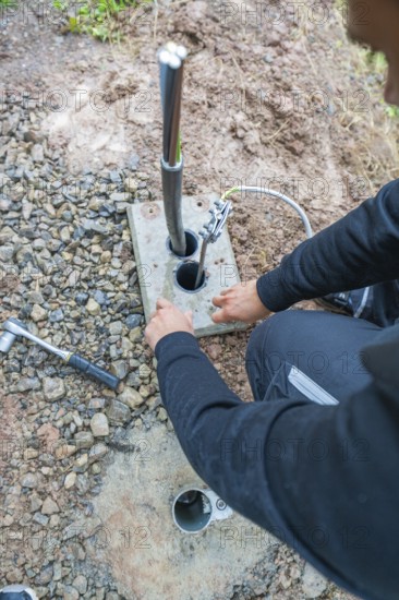Worker attaching electrical cables to a grounding device on the ground, assembly of a charging