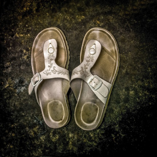 Worn sandals resting on a textured surface showcasing rustic charm and everyday wear in a casual