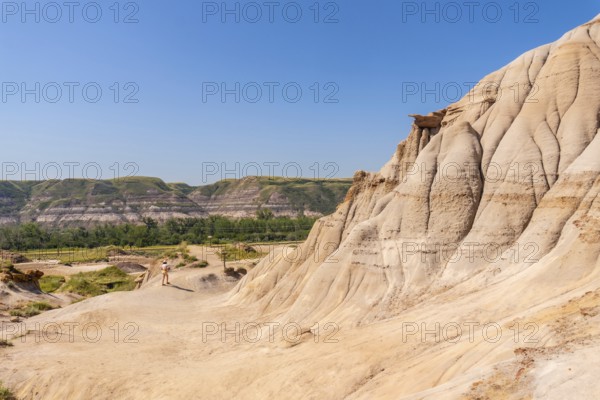 Tourist walking through the arid badlands of drumheller, alberta, surrounded by unique hoodoo