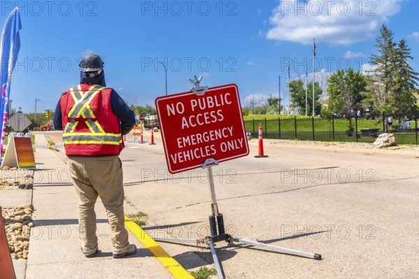 Construction worker wearing a safety vest and hardhat, standing near a no public access sign,