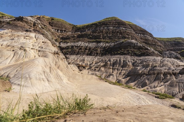 Sunlight illuminates the unique geological formations known as hoodoos, rising from the dry ground