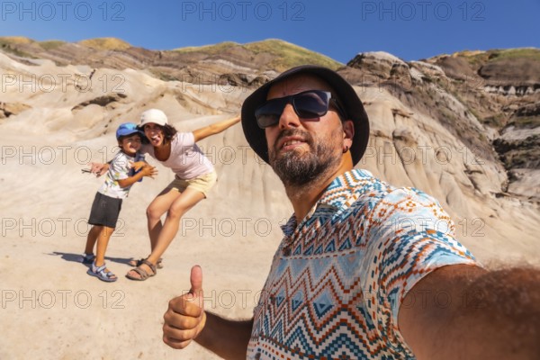 Family taking a selfie with thumbs up gesture in front of the unique hoodoos landscape of