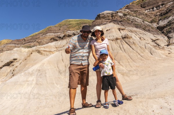 Happy family of tourists standing in front of the unique geological formations of drumheller,