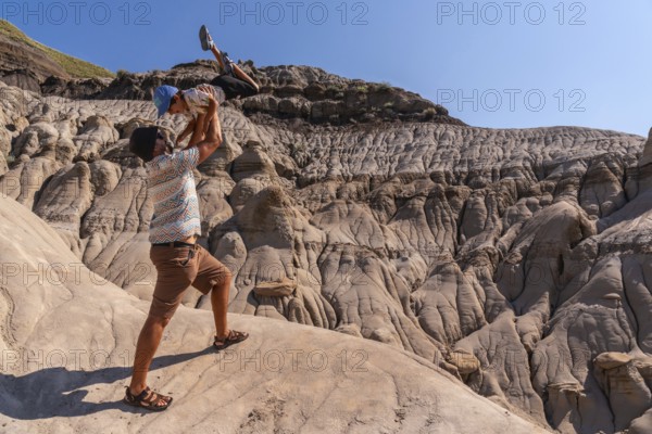 Father playfully lifting his son in the air at horseshoe canyon in drumheller, alberta, canada,