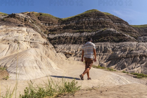 Tourist exploring the arid landscape of the canadian badlands, walking through the unique