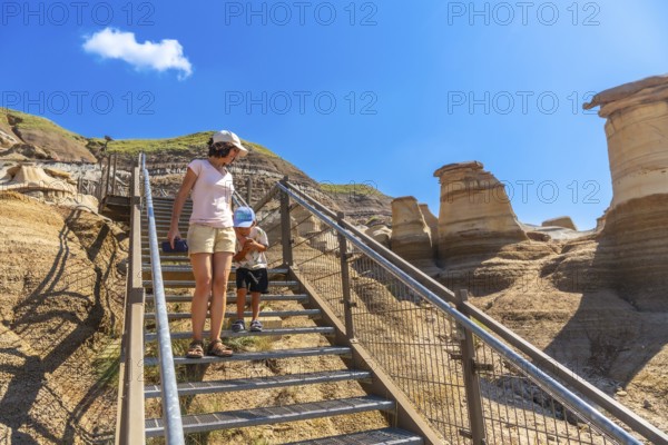 Mother and son descending metal stairs at the hoodoo trail in drumheller, alberta, canada,