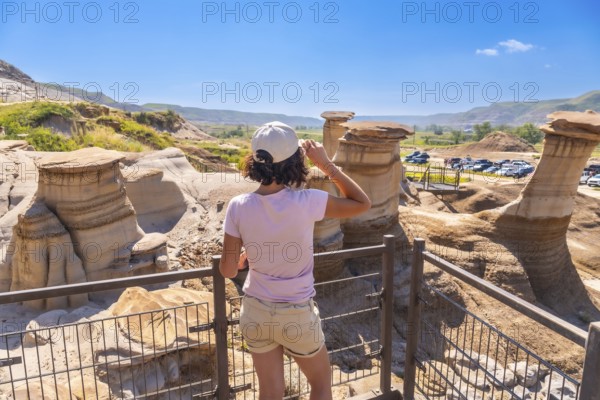 Young woman enjoying view of unique hoodoo rock formations at tourist attraction in drumheller,