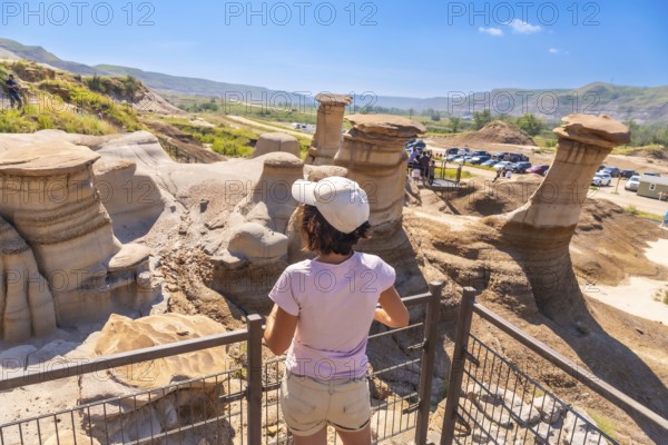 Tourist wearing a cap observing stunning hoodoo rock formations in drumheller valley, alberta,