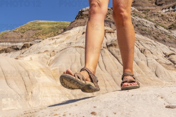 Female tourist wearing sandals walking on the rocky terrain of the hoodoos in drumheller, alberta,