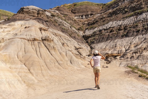 Female tourist walking and exploring horseshoe canyon in drumheller, alberta, a unique geological