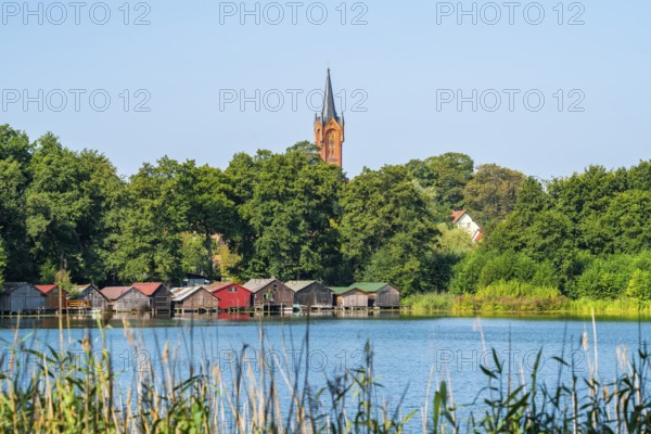 View across the Haussee to the town church and colorful boathouses on stilts, Feldberg, Feldberg