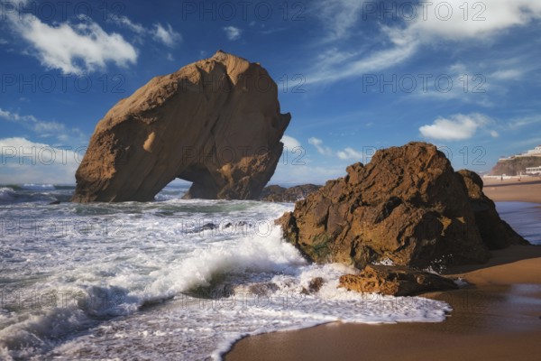 Penedo do Guincho, a large boulder rock arch at Praia da Santa Cruz, Portugal, with ocean waves and