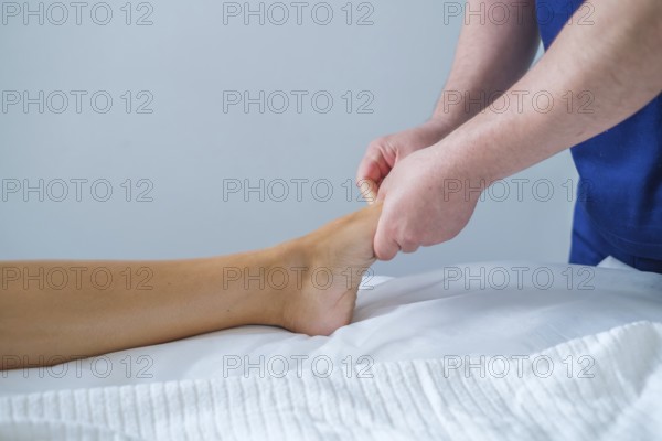 A woman enjoys a soothing foot and leg massage at a spa salon. The therapist uses oil for lymphatic