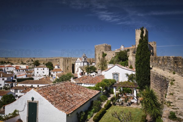 Stunning Obidos castle overlooking traditional Portuguese houses and rooftops under a clear blue