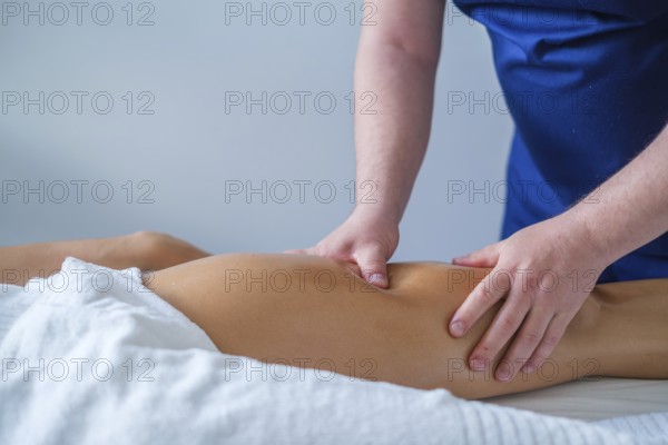 A therapist performs a soothing leg and thigh massage with oil in a spa salon. The focus is on