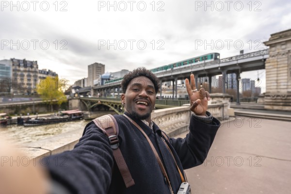 Happy african american man tourist taking a selfie portrait on a bridge over the seine river in