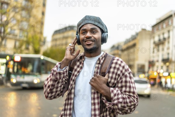 African american man feeling happy listening to music on headphones while exploring a european city