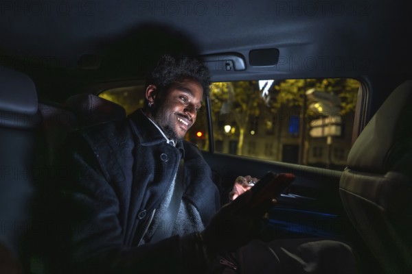 Young black man smiling and connecting with his smartphone, texting or browsing social media