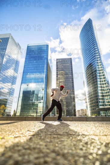 Man running with energy and freedom against a backdrop of modern glass skyscrapers, symbolizing