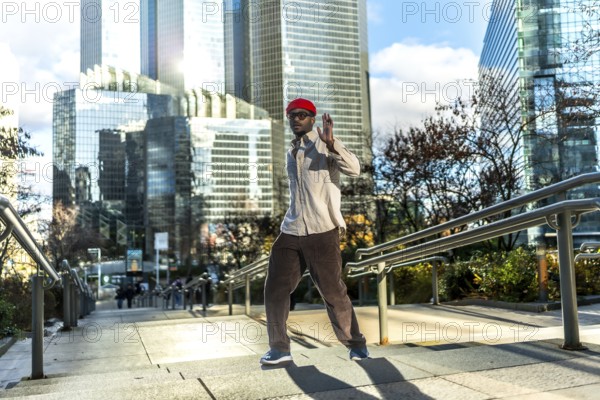 Man with red hat and sunglasses walking down an outdoor staircase in a modern central business