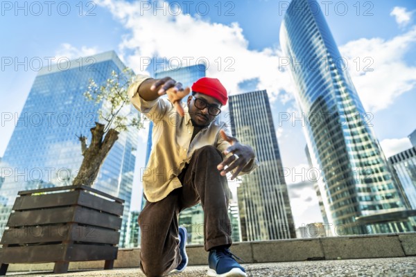 Young black man performing a dynamic street dance pose, capturing urban culture and a cool