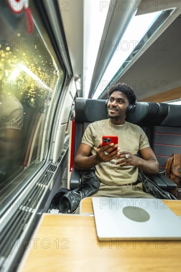 Young man wearing headphones and holding a smartphone, relaxing and enjoying the journey while