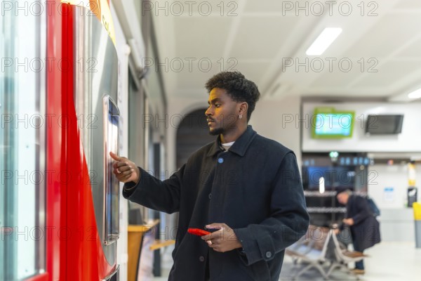 Young businessman standing at a train station, purchasing a ticket from an automatic vending