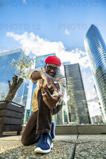 Young black man with a red beanie and glasses smiling at the camera, posing and expressing himself