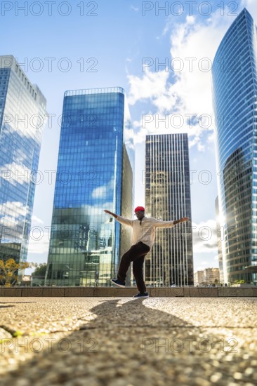 Stylish black man balancing on one leg with outstretched arms, expressing joy and freedom against a