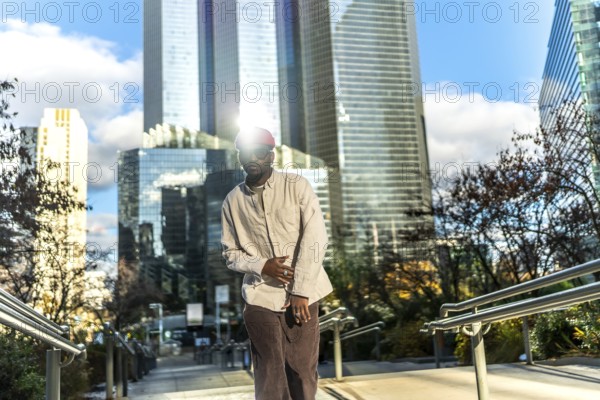 Young man wearing casual street style clothes and sunglasses, looking at camera while posing on