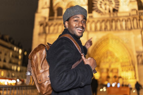 Young african american man smiling and pointing, enjoying a night out in paris and exploring an