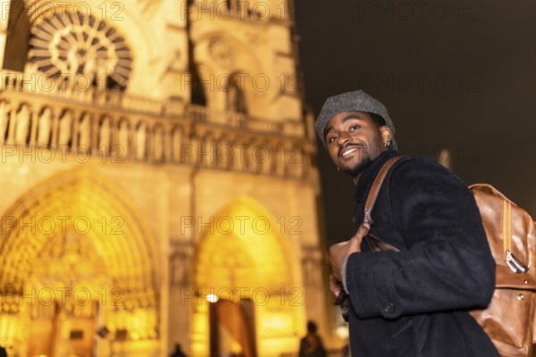 Young man smiling and wearing a backpack, exploring the historic architecture of notre dame