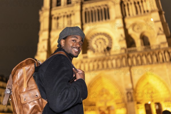 Young black man smiling, discovering french culture and history, standing in front of the
