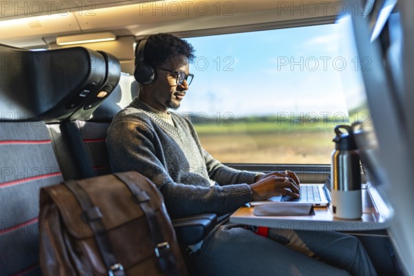 Young professional with headphones and glasses focused on laptop, working efficiently on a high