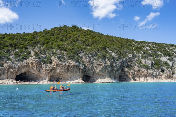 Kayakers in clear blue water, picturesque rocky coast, cliffs and Cala Luna beach, Golfo di Orosei,