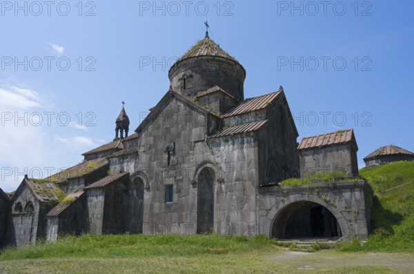 Stone monastery with several structures and domes in front of a wide meadow, Haghpat monastery,