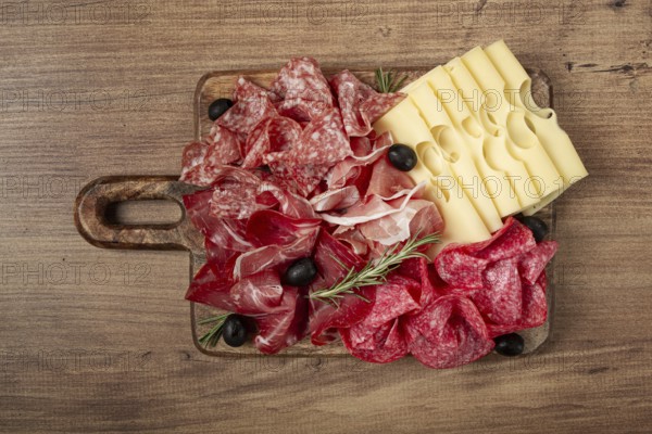 Assorted meat, appetizer, prosciutto, salami and ham, with maasdam cheese and olives, on a wooden