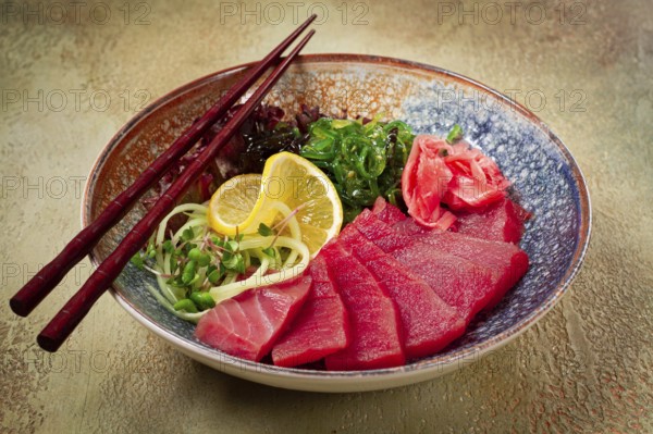 Tuna sashimi with daikon and wakame salad, pickled ginger, in a bowl