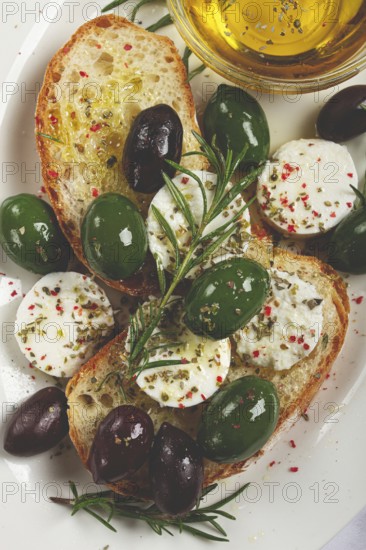 A plate with a snack, ciabatta bread with cheese and olives, olive oil, spices and herbs, top view,