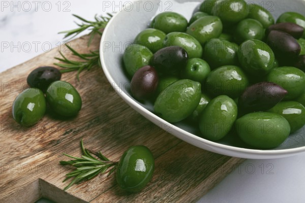 Chalkidiki olives, classic Greek green olives, in a bowl on a cutting board, top view, without