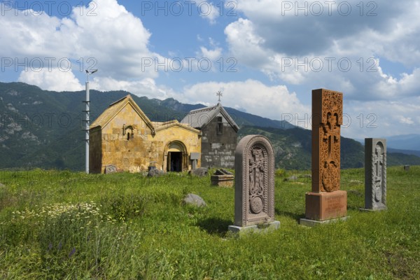 Church with stone sculptures in a green mountain landscape under a cloudy sky, Crossstones,