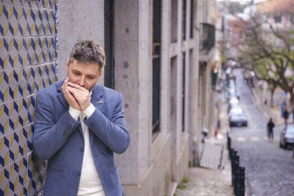 Man musician in a blue blazer and white sweater playing blues on a harmonica with eyes closed,